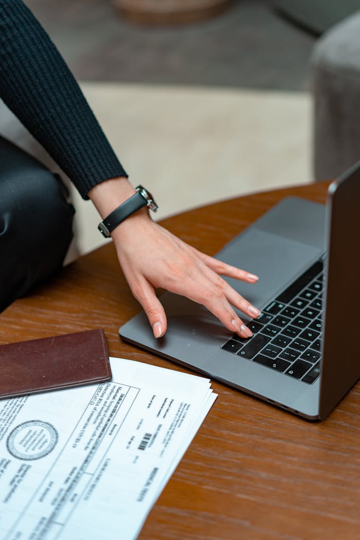 Close-up of a person typing on a laptop with legal documents on a table, showcasing work and technology integration.